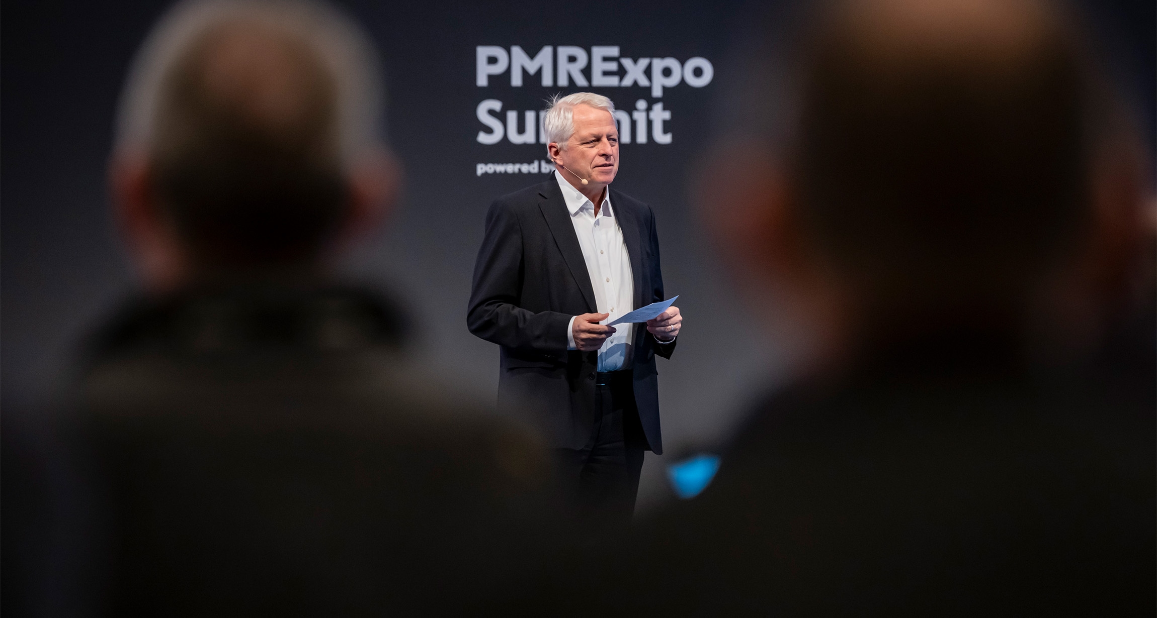 A dynamic presenter engages the audience at the PMRExpo Summit, with captivated attendees visible in the foreground eagerly absorbing the insights shared.